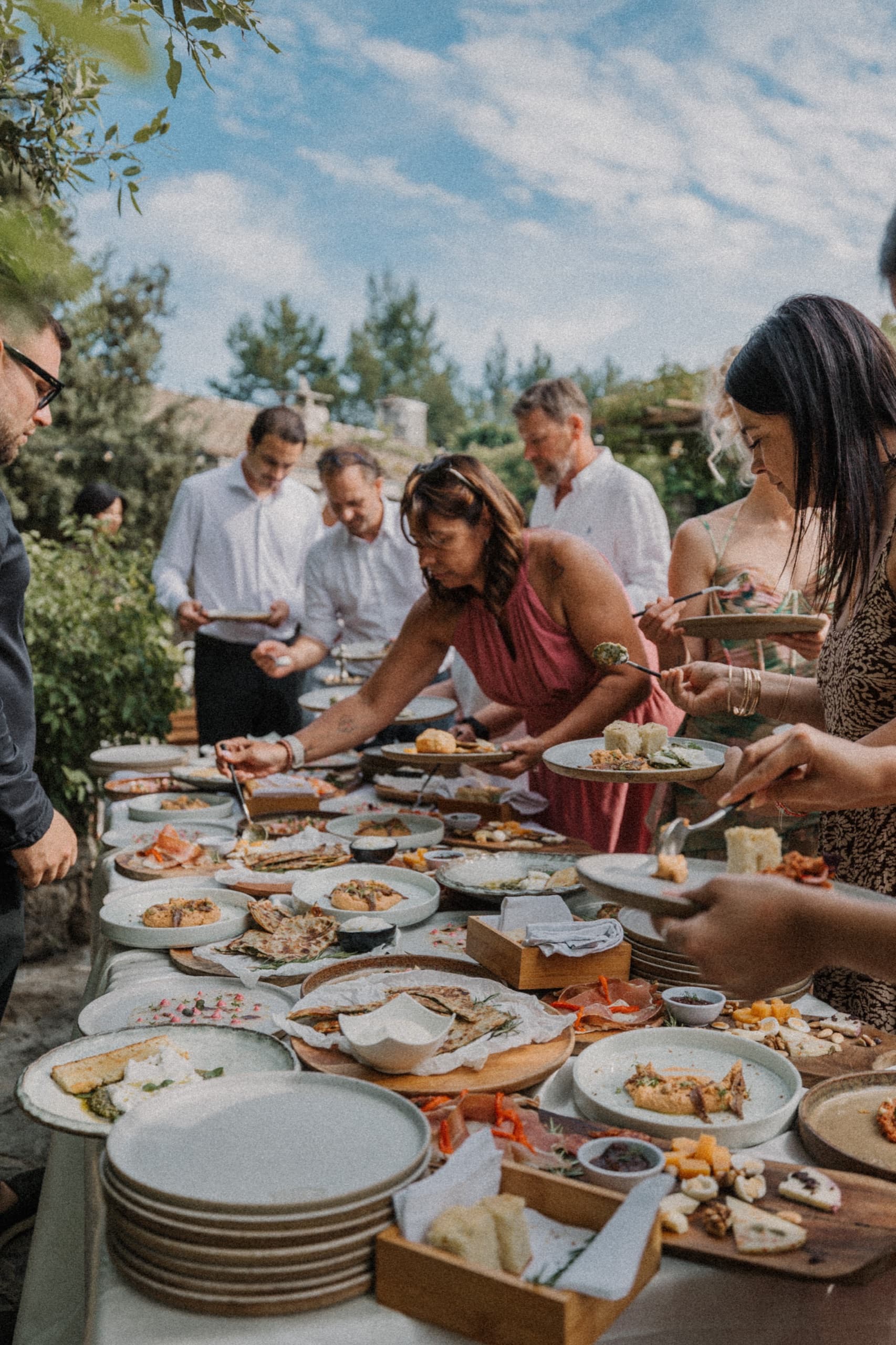 Guests gathered around a rustic banquet table laden with food