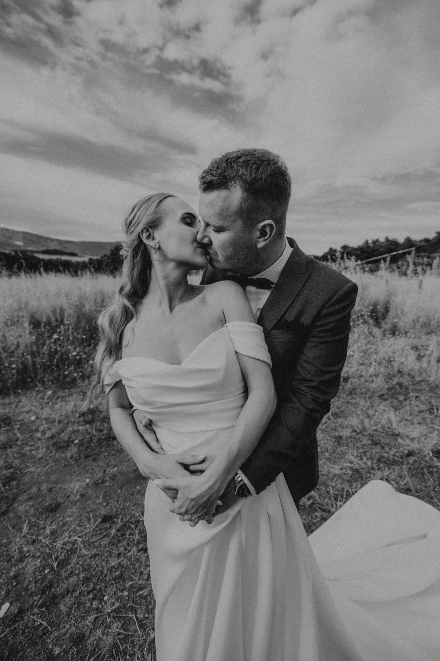 Bride and groom sharing a kiss in a golden field, black and white
