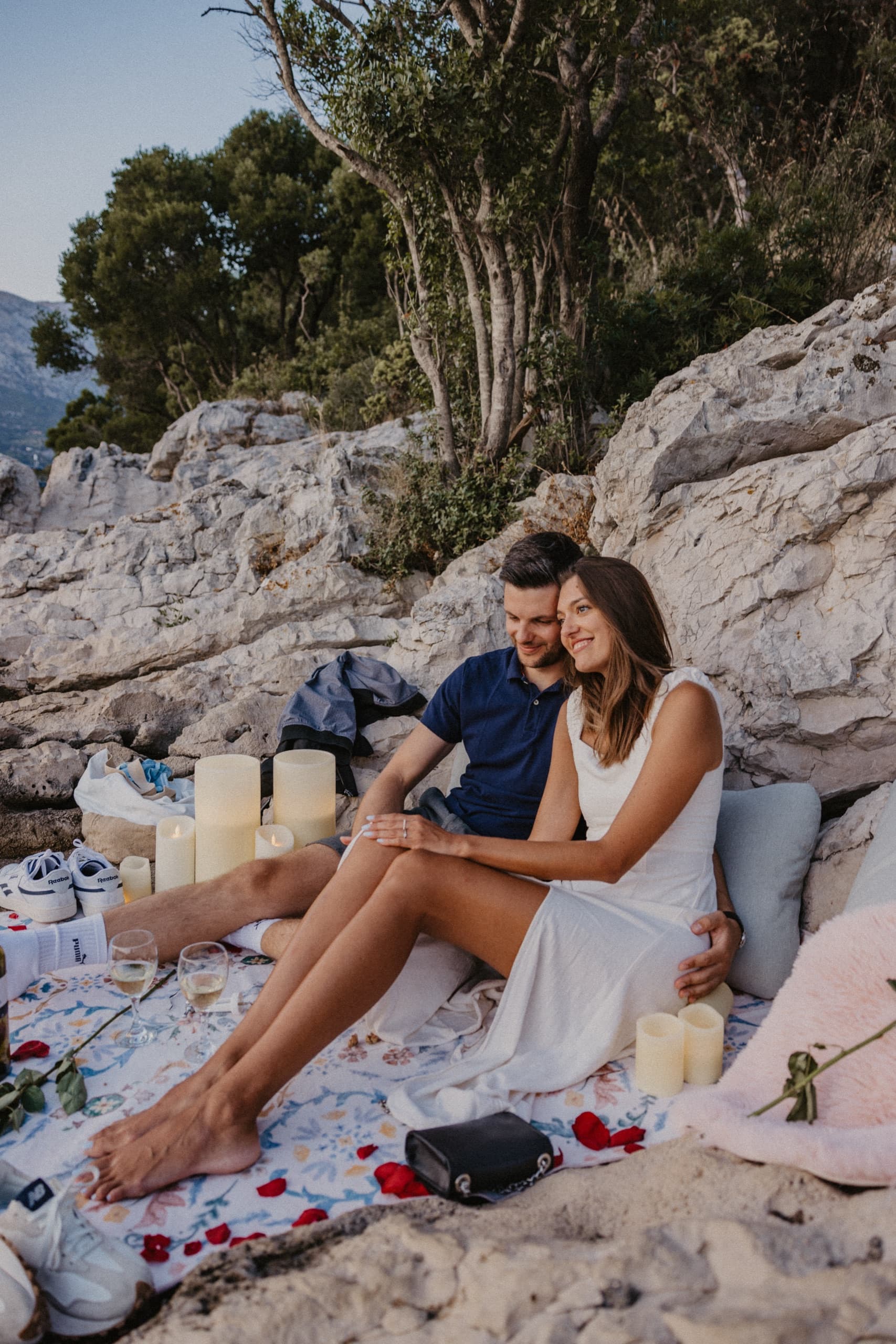 A couple on a candlelit rug among rose petals by the sea