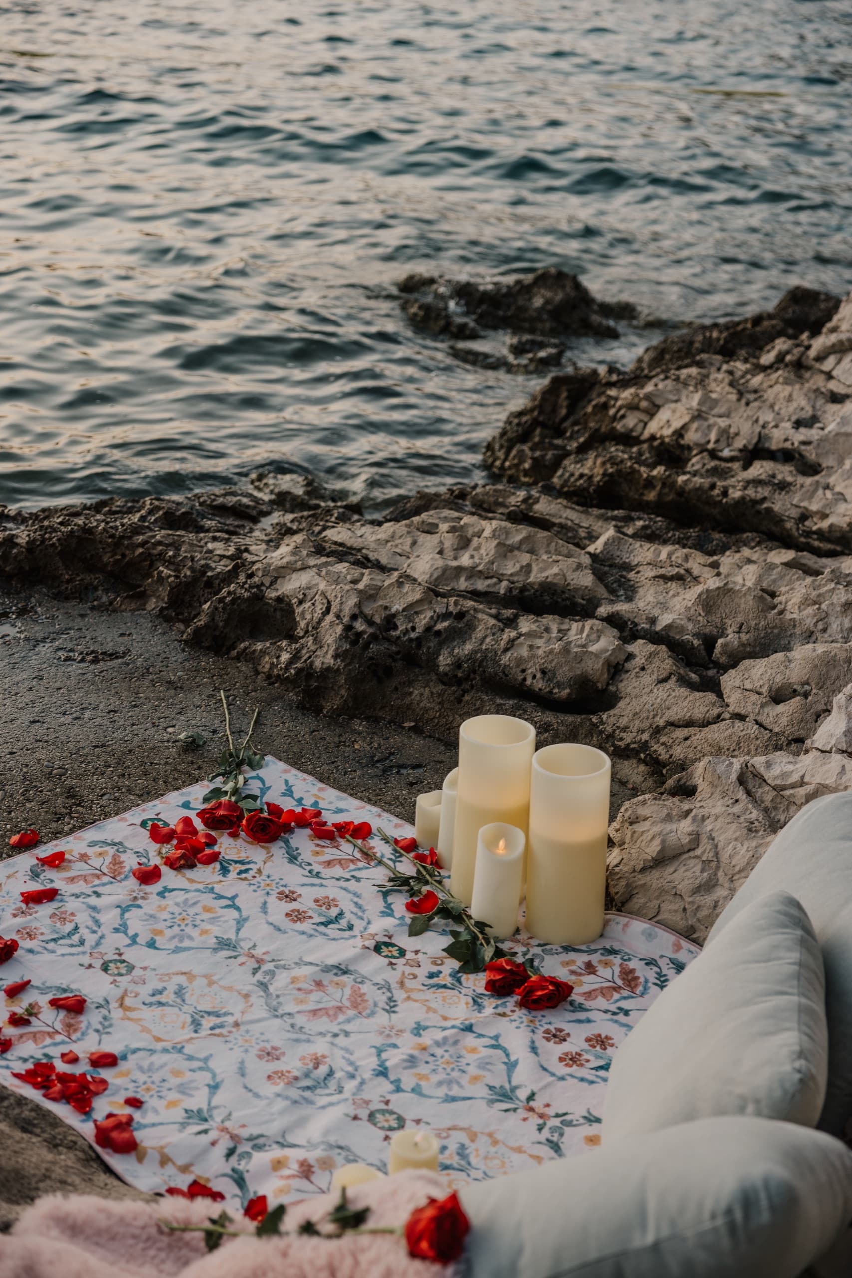 A candlelit picnic laid out on the rocks above the sea